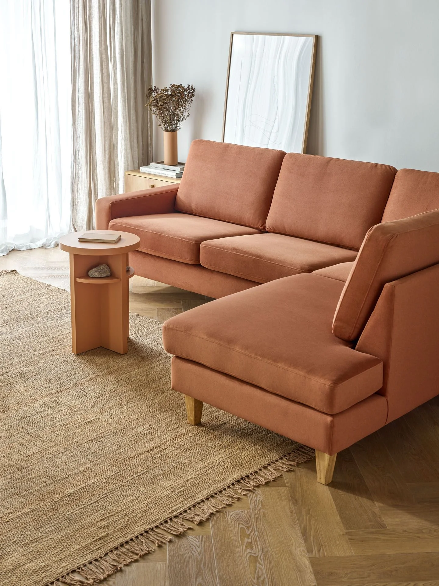 sofa z ceglastą tapicerką w jasnym salonie